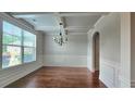 Bright dining room featuring a large window, chandelier, wainscoting, and coffered ceilings at 207 Birchwood Dr, Loganville, GA 30052