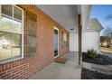 Covered front porch with brick accents, a concrete walkway, and a well-kept yard at 50 Berkshire Run, Covington, GA 30016