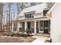 Charming front porch with white columns and black-framed windows with wooded view at 9229 Selborne Ln, Chattahoochee Hills, GA 30268