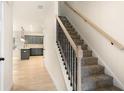 Carpeted staircase with black metal spindles and wood handrail, providing a modern transition to the upper level and kitchen view at 735 Shetland Trl, Cartersville, GA 30121