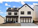 Attractive two-story home featuring a light exterior, black accents, covered porch, and a spacious two-car garage at 1590 Branthaven Ln, Auburn, GA 30011