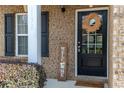 Inviting front door with brick facade, decorative wreath, welcome sign, and sidelight, offering great curb appeal at 1390 Napa Valley Sw Dr, Lawrenceville, GA 30045