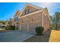 Side angle of a brick home featuring a two-car garage and well-maintained landscaping at 2045 Broadmoor Way, Fairburn, GA 30213