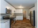 Open kitchen featuring stainless appliances, granite countertops, white cabinets and modern hardwood floors at 2303 Pinewood Dr, Decatur, GA 30032