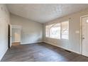 Living room with hard surface flooring, a large window with a damaged blind, and a view to a hall at 546 W Sherwood Dr, Riverdale, GA 30274