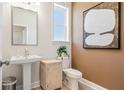 Neat half bathroom featuring a pedestal sink, decorative art, and natural light from the bright window at 3119 Shirecrest Ln, Dacula, GA 30019