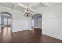 Formal dining room featuring elegant wainscoting, coffered ceilings, dark floors, and an ornate chandelier at 3313 Alhambra Cir, Hampton, GA 30228