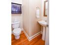 Cozy half bath with hardwood floors, pedestal sink, and dark wood storage cabinet at 160 Edgewater Trl, Fayetteville, GA 30215