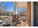 Inviting front porch featuring a seating area with iron railing, brick flooring, and classic white pillars at 3908 Charleston Market St, Suwanee, GA 30024