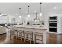 Open-concept kitchen featuring stainless steel appliances, a center island with barstool seating, and hardwood flooring at 3908 Charleston Market St, Suwanee, GA 30024