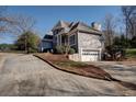 View of the home, highlighting the attached garage, gray paint, and mature landscaping at 4610 Riversound Drive, Snellville, GA 30039