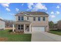 Inviting two-story home with a brick facade, a welcoming front porch with columns, and a two-car garage at 116 Dalston Cv, Stockbridge, GA 30281