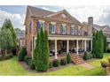 Classic brick home with a covered porch, manicured greenery, and symmetrical landscaping adding to its curb appeal at 8025 Georgetown Cir, Suwanee, GA 30024