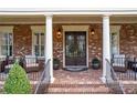 Inviting front porch with brick flooring, comfortable seating, and decorative front door with wrought iron details at 8025 Georgetown Cir, Suwanee, GA 30024