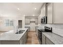 Modern kitchen with granite countertops, stainless steel appliances, and gray cabinets at 1084 Georgian Point Dr, Lawrenceville, GA 30045