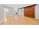 Open living room with light wood floors, recessed lighting, and a large wooden sliding barn door at 188 Triumph Nw Dr, Atlanta, GA 30327