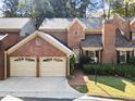 Charming brick home showcasing a two-car garage, brick chimney, and meticulously maintained landscaping at 52 Ivy Chase Ne, Atlanta, GA 30342