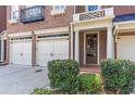 Close up of brick townhome garages, front door with wreath, and manicured landscaping at 7524 Portbury Park Ln, Suwanee, GA 30024