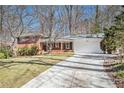 Exterior view showcasing a brick home with a long driveway leading to an attached garage at 2447 Caladium Drive Northeast, Atlanta, GA 30345