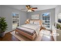 Serene bedroom with natural light from two windows and a stylish wood bed frame complemented by hardwood floors and minimalist decor at 8005 Bamby Ln, Jonesboro, GA 30236