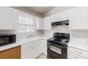 Compact kitchen featuring white cabinets, a black stove, and ample counter space at 1284 To Lani Path, Stone Mountain, GA 30083
