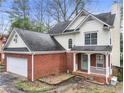 Charming home showcasing a brick facade, inviting front porch, and an attached garage with natural landscaping at 447 Hemlock Dr, Pine Lake, GA 30083