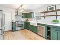 Modern kitchen with green cabinets, stainless steel appliances, farmhouse sink, and open shelving at 447 Hemlock Dr, Pine Lake, GA 30083