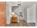 Inviting foyer with hardwood floors, elegant staircase, and a decorative cabinet, enhanced by a modern light fixture at 146 River Ridge Ln, Roswell, GA 30075