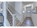 Bright foyer with staircase featuring modern wood steps and dark metal railing at 2700 Ne Almand Ln, Conyers, GA 30013