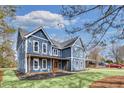 A blue two-story home featuring a welcoming front porch, well-manicured lawn, and driveway at 474 Maxwell Rd, Roswell, GA 30075