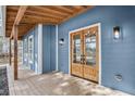 A charming covered porch with a wooden floor and an entryway with double wooden doors at 474 Maxwell Rd, Roswell, GA 30075