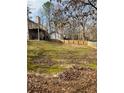 Image shows a grassy backyard, with a deck, surrounded by tall trees and a long wooden fence at 4155 Gables Pl, Buford, GA 30519
