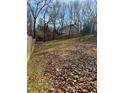 Image shows a large unfenced backyard, covered in leaves and surrounded by trees at 4155 Gables Pl, Buford, GA 30519
