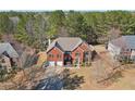 Aerial view of a two-story brick home in a wooded neighborhood, featuring an attached two-car garage at 6328 Woodlore Nw Dr, Acworth, GA 30101