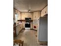 Outdated kitchen area with beige cabinets, appliances, and outdated flooring at 5581 Shadow Rock Dr, Lithonia, GA 30058