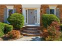 Close-up of the front entrance with brick steps, decorative shrubbery, and elegant wall-mounted lanterns at 1655 Pine Ridge Cir, Woodstock, GA 30188
