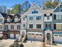View of townhomes featuring multi-car garages, classic architecture, and mature trees at 244 Trecastle Sq, Canton, GA 30114