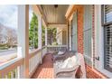 Inviting front porch with brick flooring, comfortable wicker chairs, and traditional white railing and columns at 730 Jackson Miller Cir, Powder Springs, GA 30127