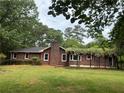 Exterior view of a single-story brick home with red shutters surrounded by lush greenery at 308 Tulipwood Sw Cir, Conyers, GA 30094