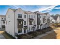 Angle view of townhomes featuring white brick exterior, dark trim, and professionally landscaped front yards at 532 Healy Dr # 61, Cumming, GA 30040