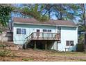 Backyard view of a cozy home, featuring a wooden deck, well-maintained lawn and natural surroundings at 5087 Fairmont Se Rd, Smyrna, GA 30082