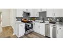Updated kitchen features stainless steel appliances, white cabinets, modern backsplash, and luxury vinyl flooring at 1069 Falling Water Se Dr, Smyrna, GA 30080