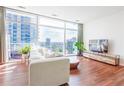 Stylish living room showcasing floor-to-ceiling windows with city views, hardwood floors, and a white sectional sofa at 45 Ivan Allen Jr Nw Blvd # 1908, Atlanta, GA 30308