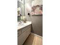 Well lit bathroom with elegant vanity, white cabinets, light walls and a large painting at 3148 Glenloch Pl, Lawrenceville, GA 30044