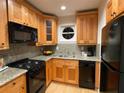 Well-lit kitchen featuring wood cabinets, granite countertops, and black appliances at 5400 Roswell Rd # K1, Atlanta, GA 30342