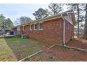 A view of the brick home's rear exterior, featuring a small deck and a well-maintained yard with mature trees at 2924 Vogue Dr, Douglasville, GA 30134