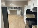 Well-lit kitchen with white cabinets, black appliances and black tiled backsplash at 4502 Cherie Glen Trl, Stone Mountain, GA 30083