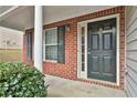 Close-up of front door with brick siding, a white column, and manicured bushes at 4607 Ravenwood Loop, Union City, GA 30291