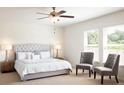 Bright main bedroom featuring a plush bed, two chairs, and two windows at 147 Silverton Dr, Dacula, GA 30019