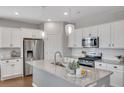 Modern kitchen featuring white cabinets, granite countertops, stainless steel appliances, and stylish pendant lighting at 5345 Coltman Dr, Cumming, GA 30028